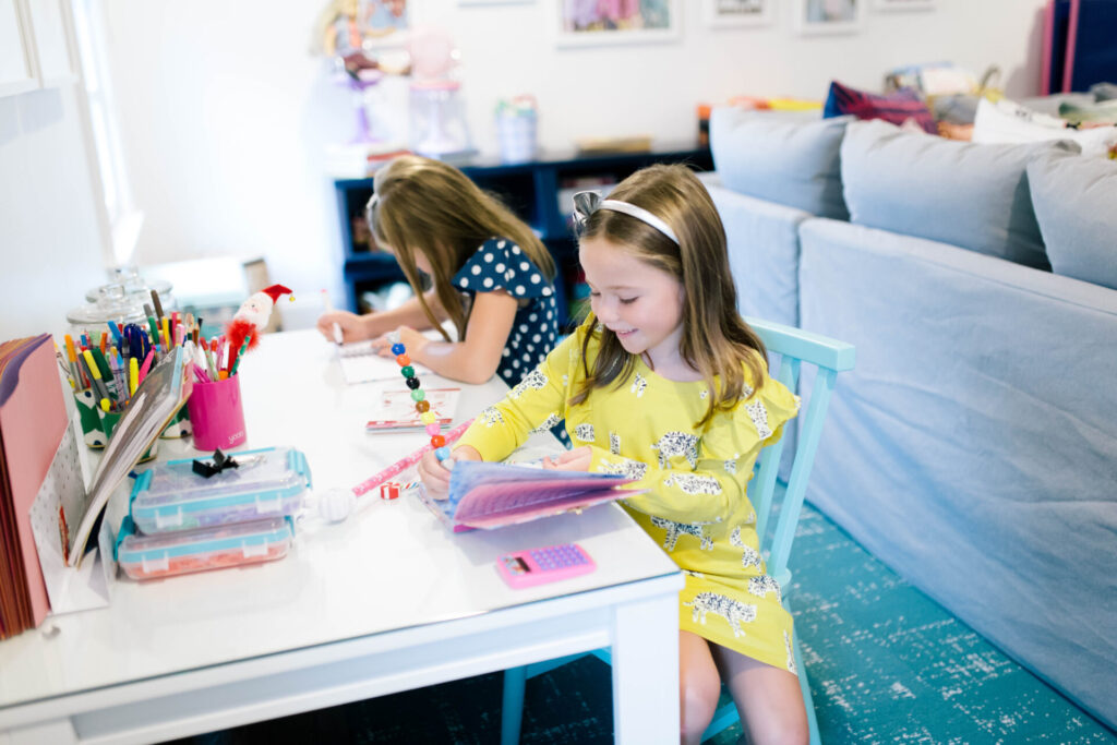 Home School Tips by popular Nashville lifestyle blog, Hello Happiness: image of two young girls doing school work at a Crate and Kids adjustable white desk and sitting in Crate and Kids Shore Light Blue Kids Chair.