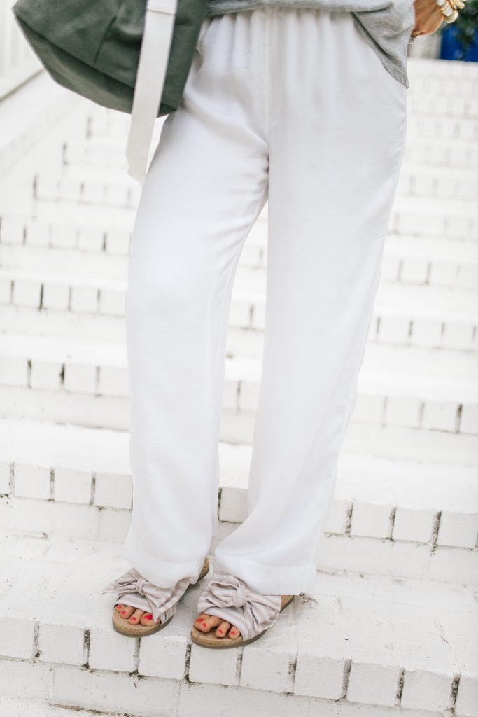 We Dress America + Walmart Travel Style for a Successful Getaway by top US fashion blog, Hello Happiness: image of woman  wearing white pants and tan and white stripe slide sandals with bow decals.