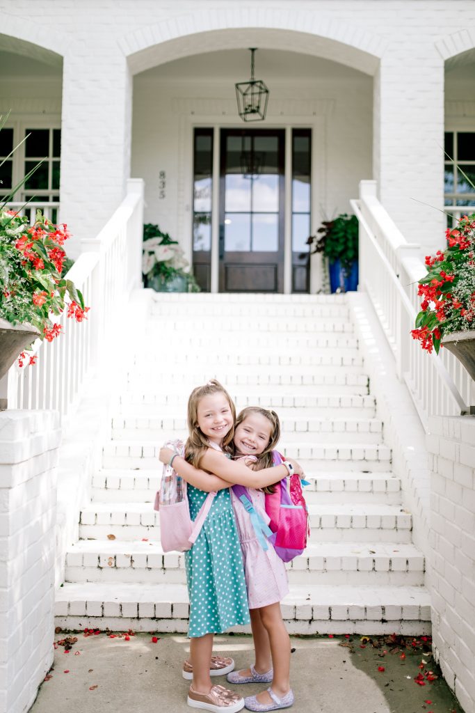 Trend Setting Back-to-School Outfits from Walmart by popular Nashville fashion blog, Hello Happiness: image of two girls wearing back-to-school outfits from Walmart and hugging each other in front of their house.