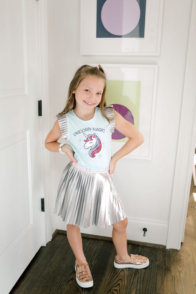 Trend Setting Back-to-School Outfits from Walmart by popular Nashville fashion blog, Hello Happiness: image of a girl wearing Walmart 365 Kids From Garanimals Shimmer Foil Pleated Skirt and 365 Kids From Garanimals Flutter Graphic Tank Top. 