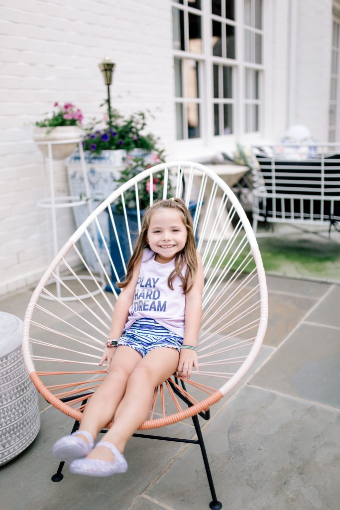 Trend Setting Back-to-School Outfits from Walmart by popular Nashville fashion blog, Hello Happiness: image of girl sitting outside in a chair and wearing Walmart Athletic Works Graphic Active Tank Racer Back and Athletic Works Active Running Shorts.