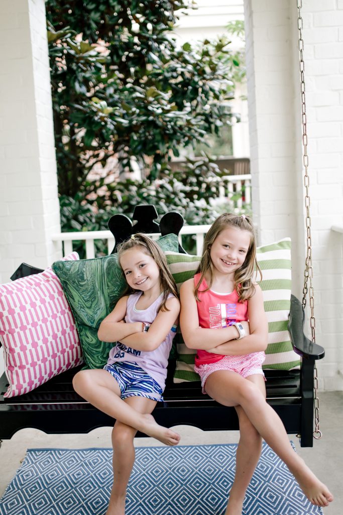 Trend Setting Back-to-School Outfits from Walmart by popular Nashville fashion blog, Hello Happiness: image of two girls sitting outside on a front porch swing and wearing Walmart Athletic Works Graphic Active Tank Racer Back and Athletic Works Active Running Shorts.
