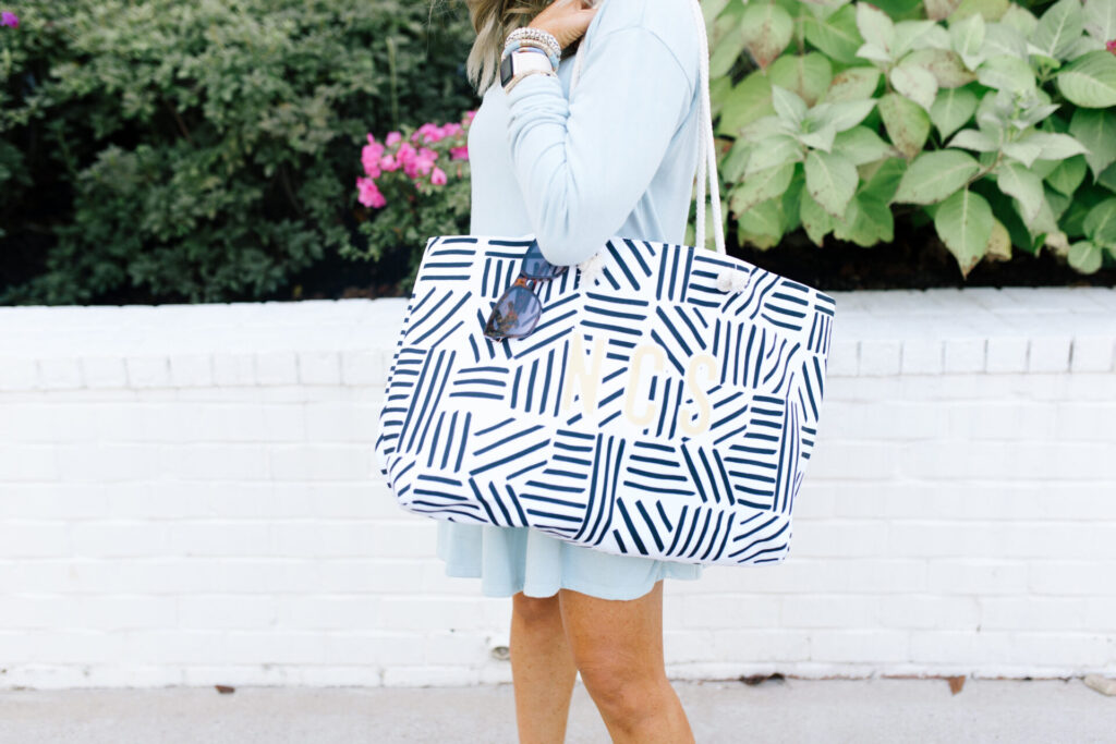 Clairebella Studio by popular Nashville life and style blog, Hello Happiness: image of Natasha Stoneking standing outside and holding a Clairebella X Hello Happiness travel tote. 