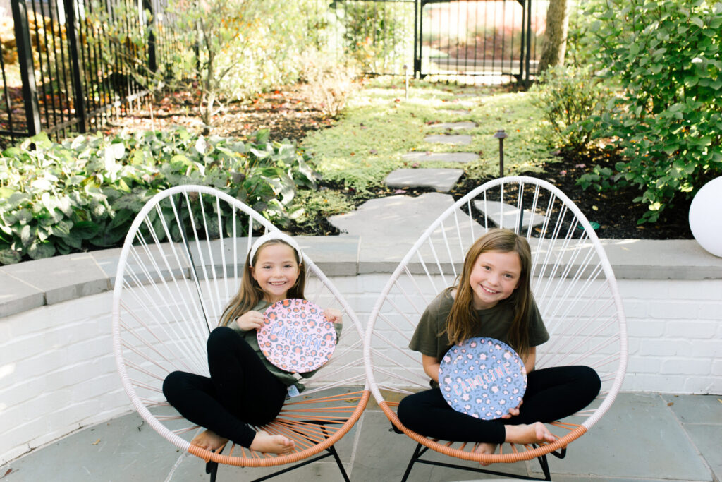 Clairebella Studio by popular Nashville life and style blog, Hello Happiness: image of two girls sitting outside and each holding a Clairebella Studio and Hello Happiness personalized dinner plate. 