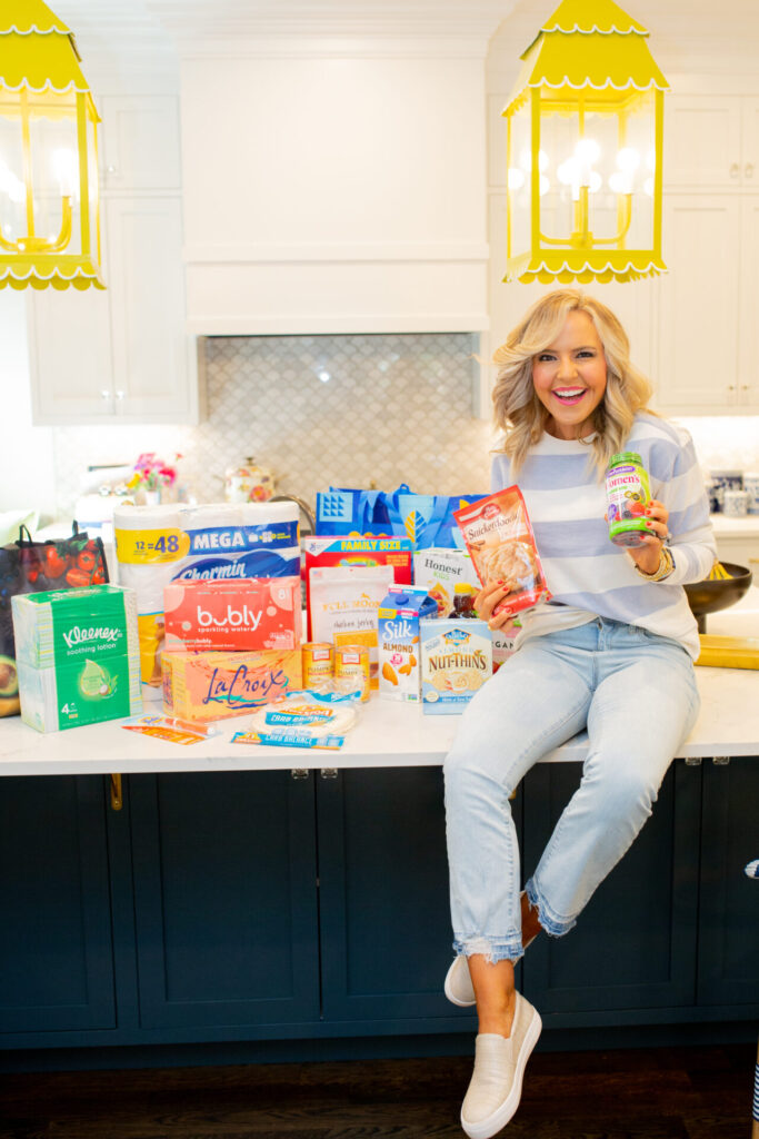 Walmart Membership by popular Nashville lifestyle blog, Hello Happiness: image of Natasha Stoneking sitting on her kitchen island that's covered with Kleenex, Bubly, La Croix, Mission tortillas, Charmin mega roll toilet paper, Betty Crocker snickerdoodle mix, Almond things, Libby's canned pumpkin, Mrs. ButterWorth's syrup, Lucky Charms cereal and Tide to-go stick. 