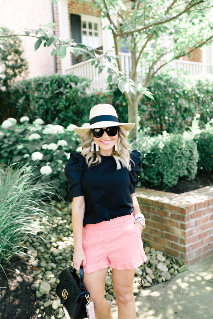 Amazon Favorites by popular Nasvhille life and style blog, Hello Happiness: image of a woman standing outside and wearing a Amazon Pineapple&Star Sun Straw Fedora Beach Hat, Amazon English Factory Women's Knit with Poplin Mixed Top, pink shorts, and holding a Gucci bag. 