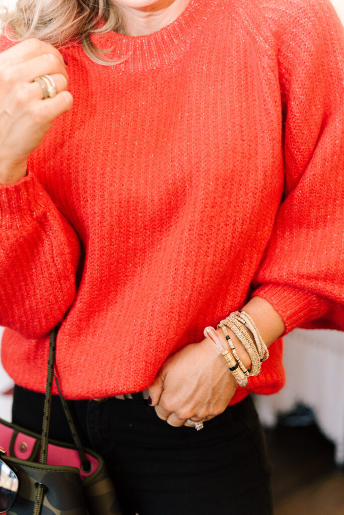 Last Minute Gift Ideas by popular Nashville life and style blog, Hello Happiness: image of Nastasha Stoneking wearing a red balloon sleeve sweater, gold bracelets, and black jeans. 