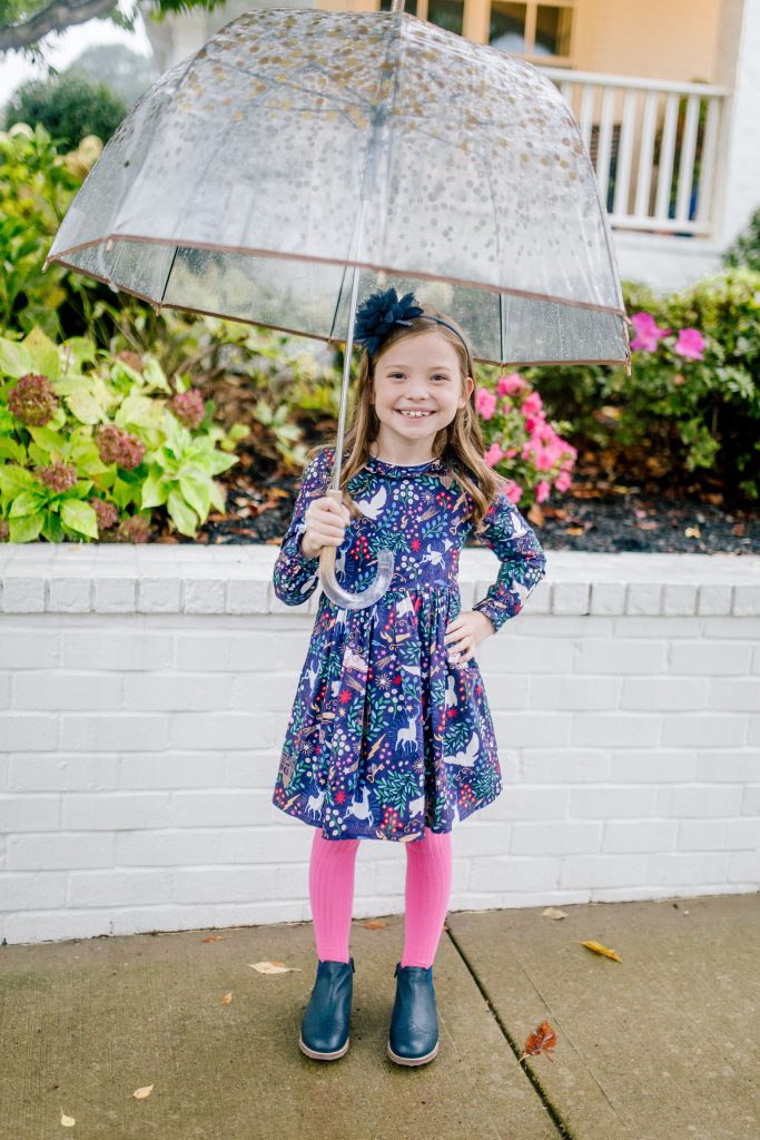 Party-Worthy Looks with the Boden Harry Potter Collection by popular Nashville fashion blog, Hello Happiness: image of a girl standing outside with an umbrella and wearing a Boden Forbidden Forest Dress, Boden pink sorbet Ribbed Tights, and Boden navy blue Leather Chelsea Boots.