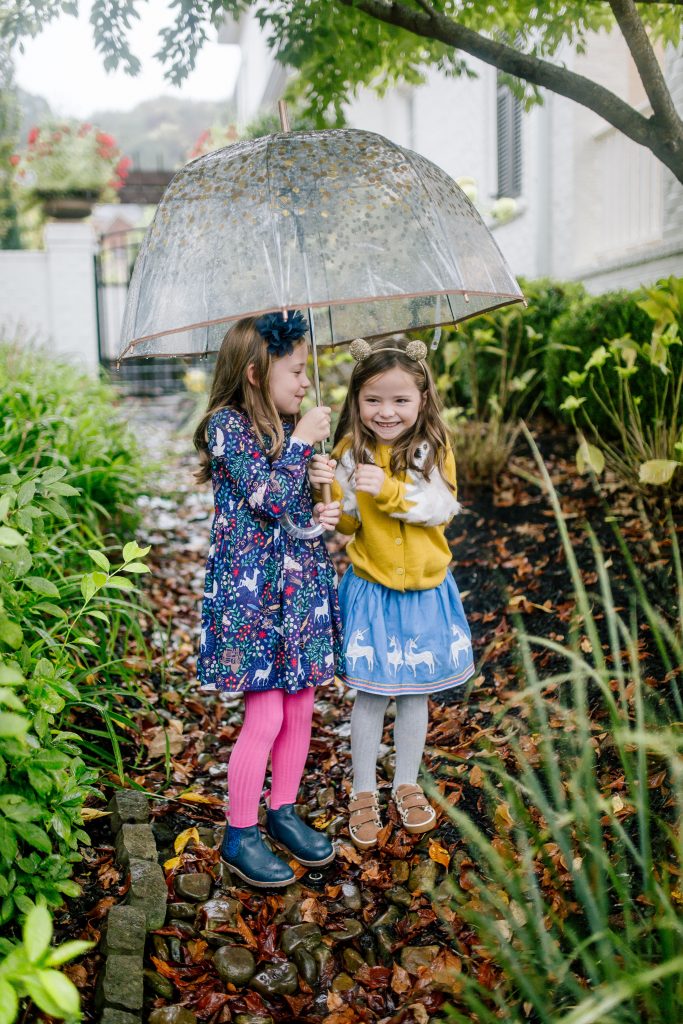 Party-Worthy Looks with the Boden Harry Potter Collection by popular Nashville fashion blog, Hello Happiness: image of two girls standing outside with an umbrella and wearing a Boden Hedwig Cardigan, Boden Appliqué Hem Skirt, Boden Grey Marl Ribbed Tights, Boden Fun Low Tops, Boden Forbidden Forest Dress, Boden pink sorbet Ribbed Tights, and Boden navy blue Leather Chelsea Boots.