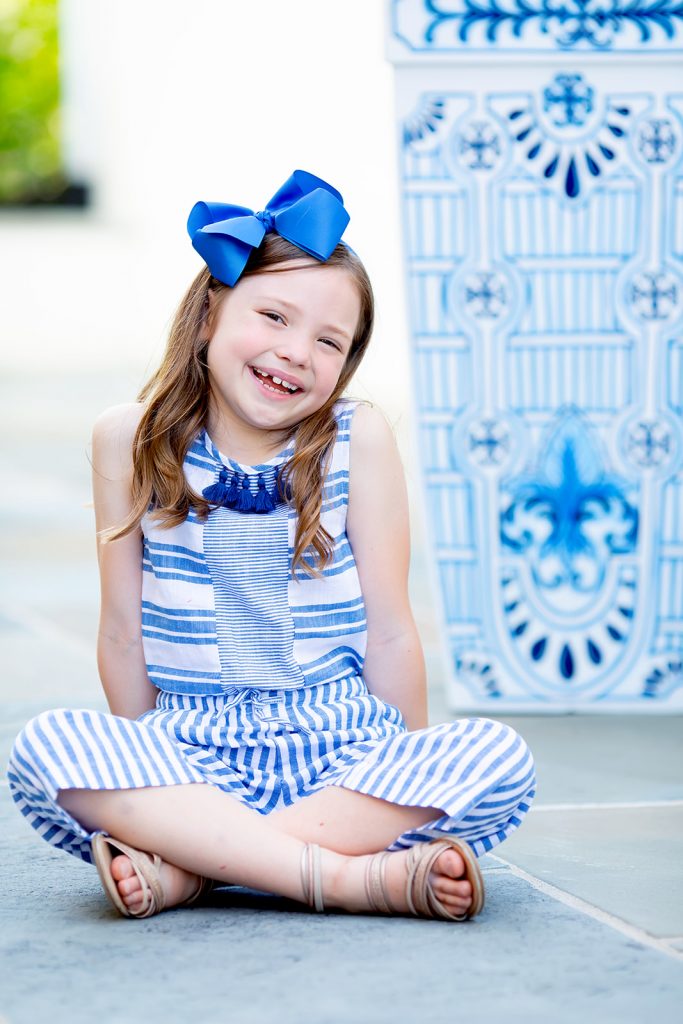 Ready, Set, SHOP! The Best in 4th of July Sales by popular Nashville fashion blog, Hello Happiness: image of a young girl sitting cross legged in front of an oriental planter and wearing a Culotte Jumpsuit.