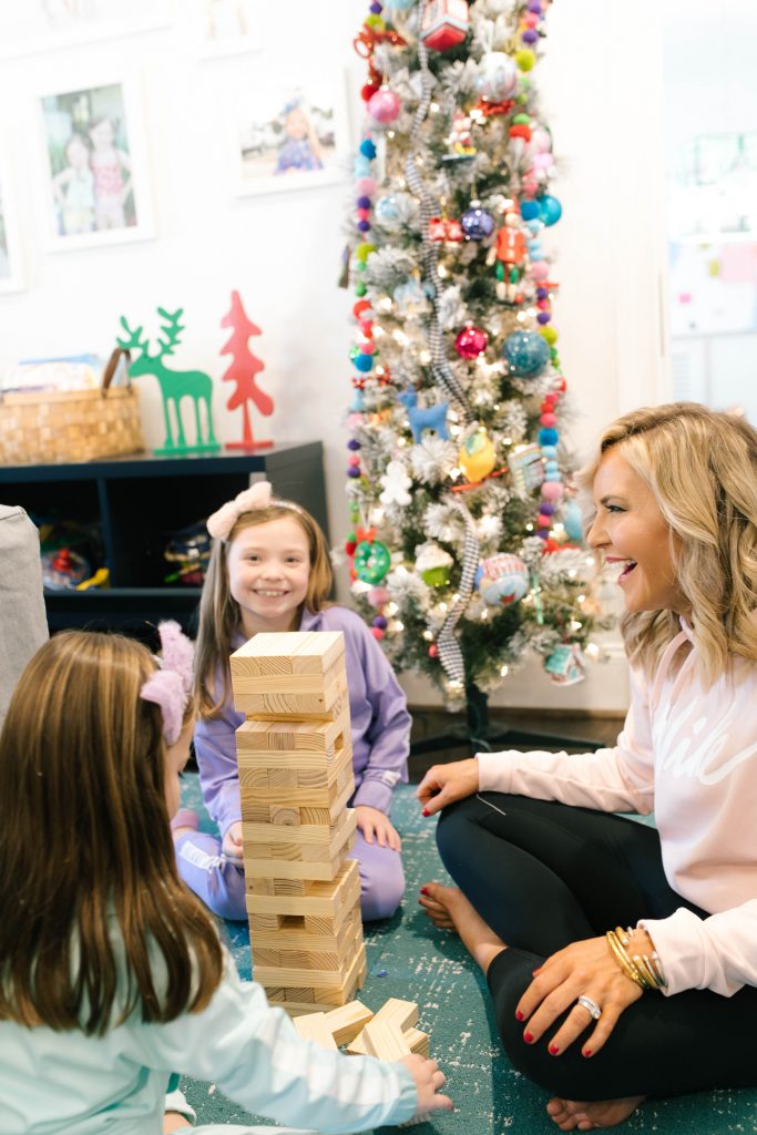 Everything Holiday with Academy Sports + Outdoors Gifts by popular life and style blog, Hello Happiness: image of a mom and her two daughters playing with a Academy Sports + Outdoors giant toppling tower.
