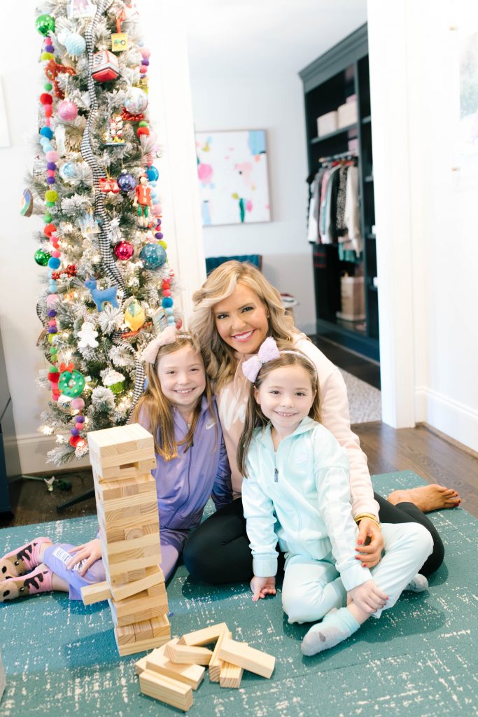 Everything Holiday with Academy Sports + Outdoors Gifts by popular life and style blog, Hello Happiness: image of a mom and her two daughters playing with a Academy Sports + Outdoors giant toppling tower.