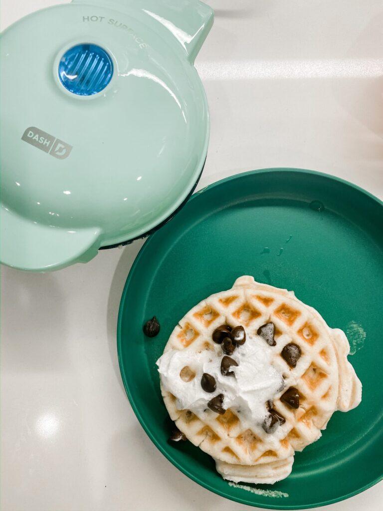 Amazon Favorites by popular Nasvhille life and style blog, Hello Happiness: image of Amazon Dash mini waffle iron and a waffle with whipped cream and chocolate chip toppings. 