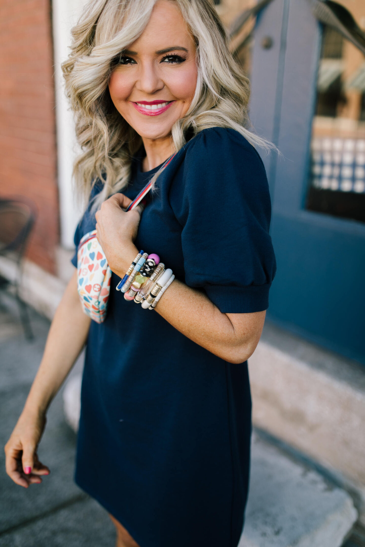 Collaborations and Partnerships by popular Nashville lifestyle blog, Hello Happiness: image of a woman wearing a black puff sleeve dress, stretch bracelets and a heart print bag. 