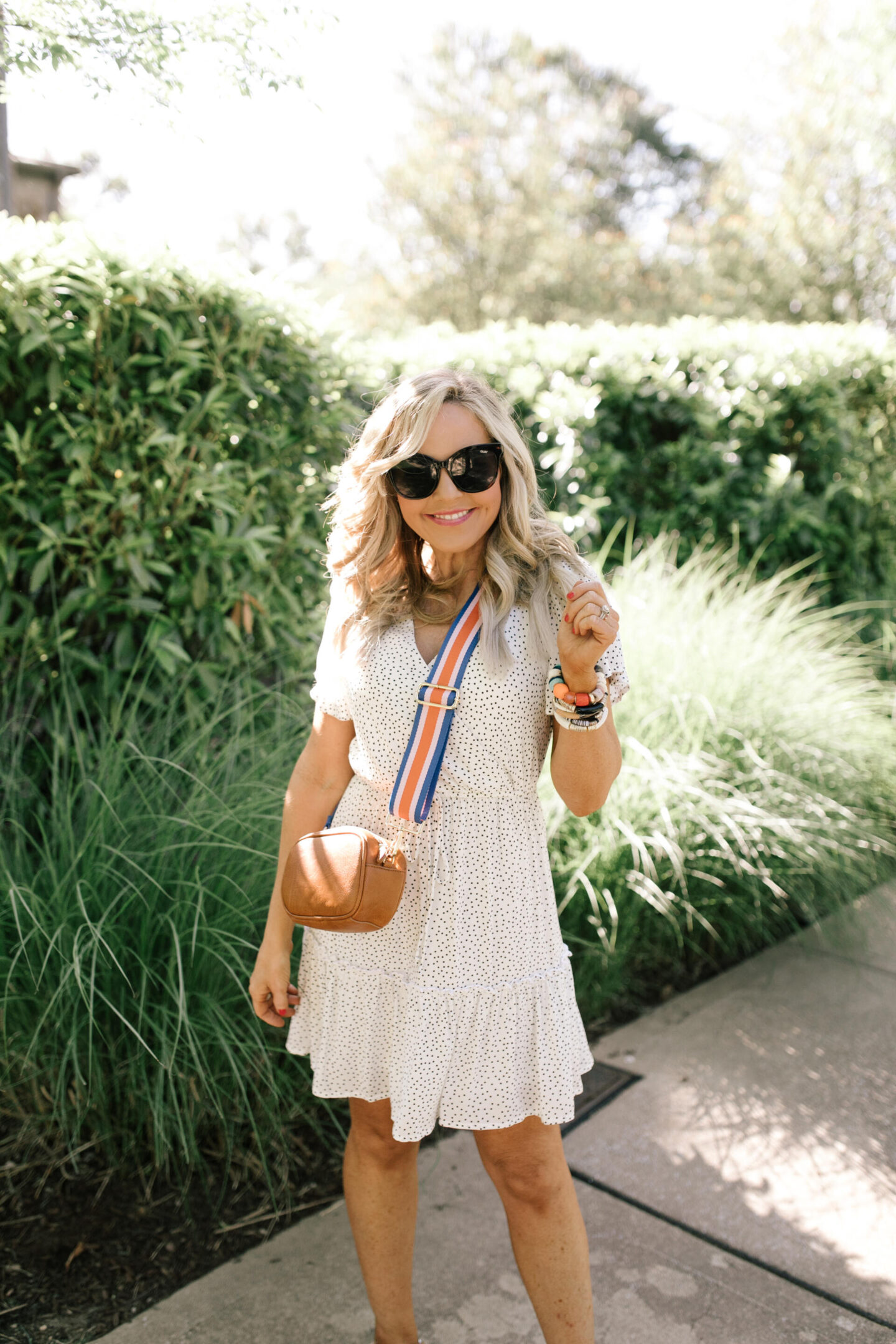 Memorial Day Sales by popular Nashville life and style blog, Hello Happiness: image of Natasha Stoneking wearing a black and white polka dot dress and brown purse with a Social Threads blue, orange, and white stripe purse strap. 