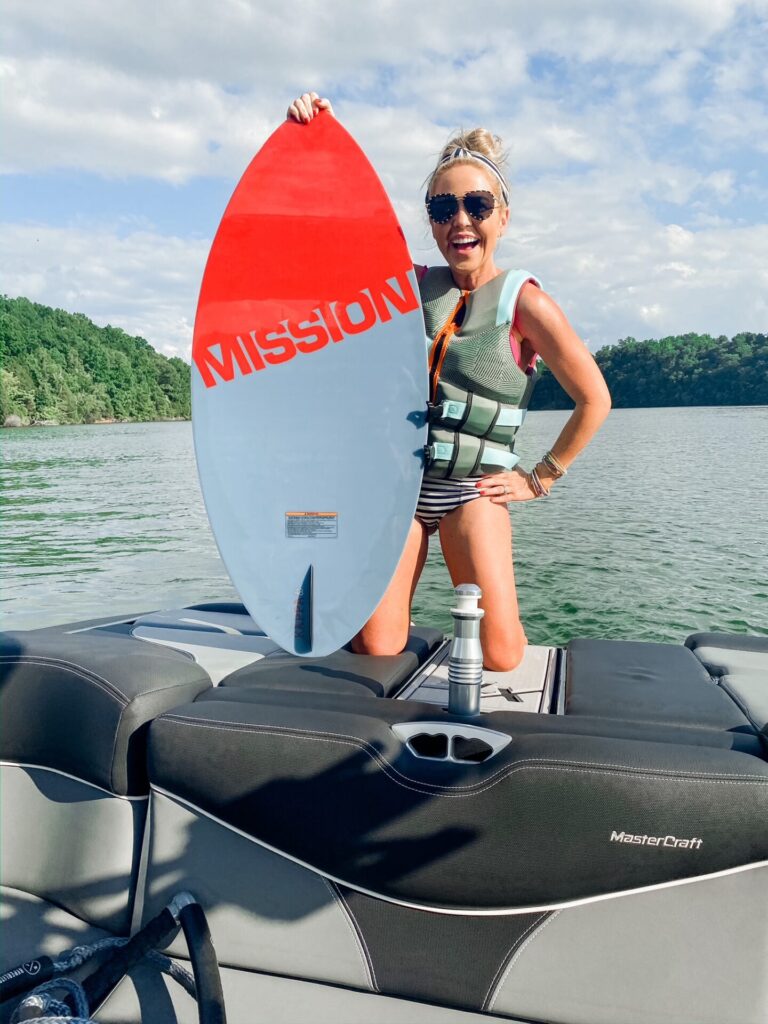 Year in Review by popular Nashville lifestyle blog, Hello Happiness: image of Natasha Stoneking kneeling on the back of a boat and holding a Mission board. 