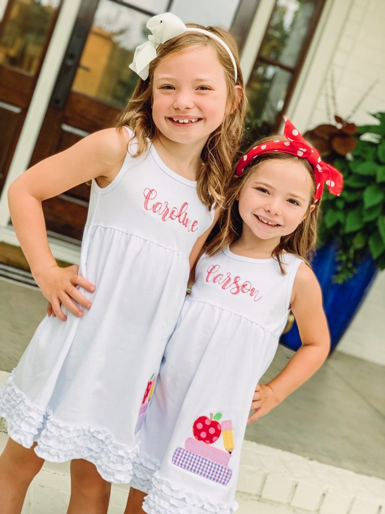 Caroline and Carson Go Back to School... And They're Off! by popular Nashville blog, Hello Happiness: image of two girls standing next to each other and wearing custom Elegant Goods Shop dresses.