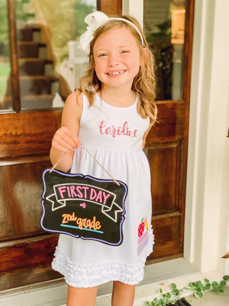 Caroline and Carson Go Back to School... And They're Off! by popular Nashville blog, Hello Happiness: image of a little girl wearing an Elegant Goods Shop dress and holding a Lovely Little Designs chalkboard sign. 