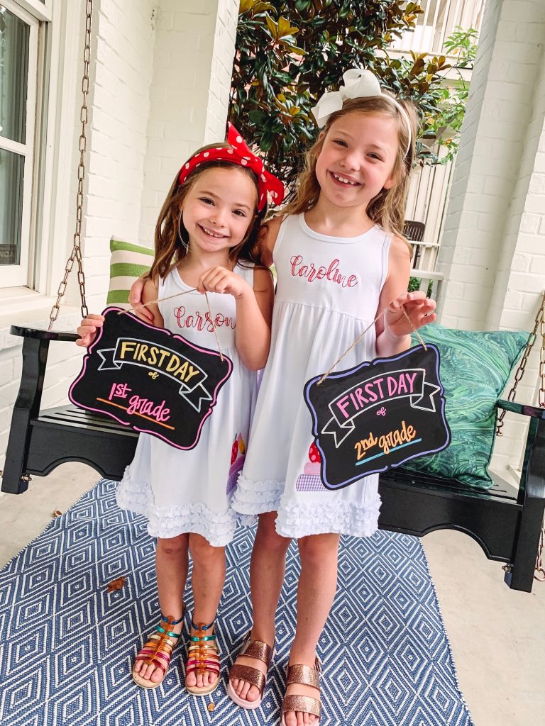 Caroline and Carson Go Back to School... And They're Off! by popular Nashville blog, Hello Happiness: image of two little girls wearing an Elegant Goods Shop dress and holding a Lovely Little Designs chalkboard sign. 
