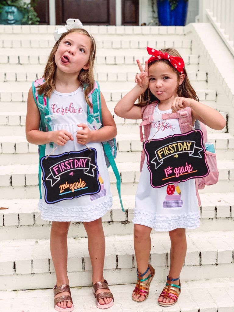 Caroline and Carson Go Back to School... And They're Off! by popular Nashville blog, Hello Happiness: image of two little girls wearing an Elegant Goods Shop dress and holding a Lovely Little Designs chalkboard sign. 