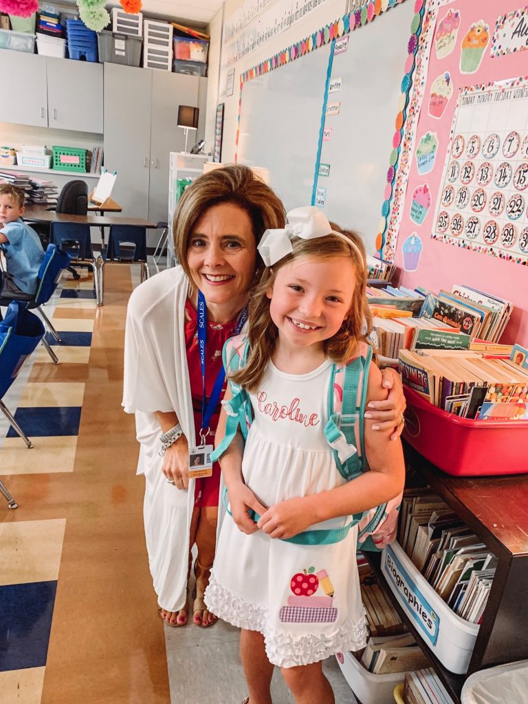 Caroline and Carson Go Back to School... And They're Off! by popular Nashville blog, Hello Happiness: image of a little girl standing inside with their teacher and wearing an Elegant Goods Shop dress.