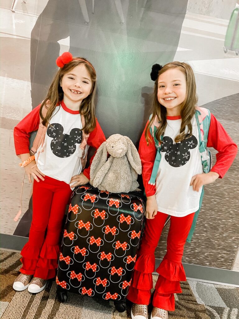 Disney Creators Celebration by popular Nashville lifestyle blog, Hello Happiness: image of two girls wearing matching Mickey Mouse shirts and standing next to a Minnie Mouse suitcase. 