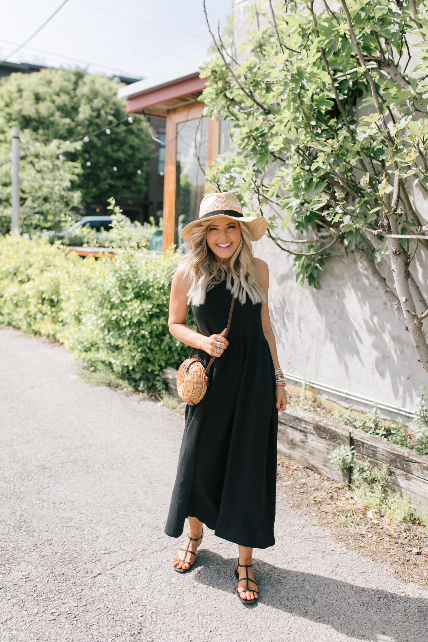 J Crew Clothing by popular Nashville fashion blog, Hello Happiness: image of a woman wearing a black J. Crew sleeveless maxi dress with black strap sandals and a straw sun hat. 