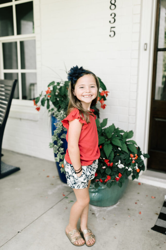Walmart School Clothes by popular Nashville fashion blog, Hello Happiness: image of a young girl standing outside and wearing a pair of Walmart Cotton On Kids Girls Callie Play Shorts and a Walmart Cotton On Kids Girls Kaia Tank Top.