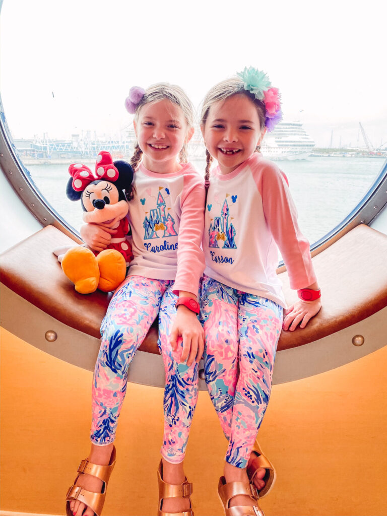 Disney Creators Celebration by popular Nashville lifestyle blog, Hello Happiness: image of two girls holding a Minnie Mouse doll and sitting in a large port key window on a Disney Cruise Ship. 