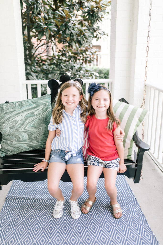 Walmart School Clothes by popular Nashville fashion blog, Hello Happiness: image of two sisters sitting together on a black front porch swing. 