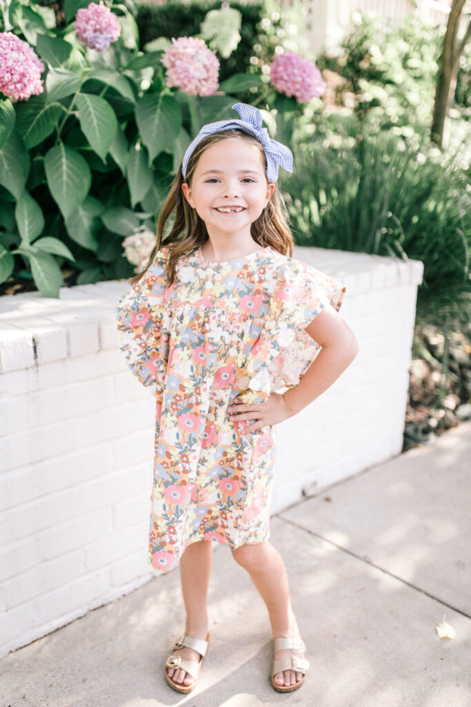 Walmart School Clothes by popular Nashville fashion blog, Hello Happiness: image of a young girl standing outside and wearing a Walmart Cotton On Kids Girls Maggie Flutter Sleeve Dress.