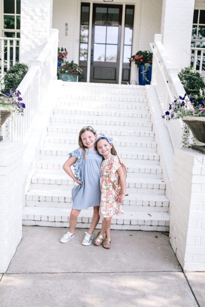 Walmart School Clothes by popular Nashville fashion blog, Hello Happiness: image of two sisters standing together in an embrace and wearing Walmart Cotton On Kids Girls Maggie Flutter Sleeve Dresses.