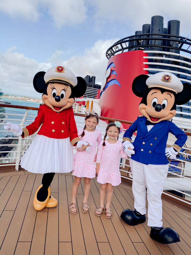 Disney Creators Celebration by popular Nashville lifestyle blog, Hello Happiness: image of two girls wearing matching pink and white dresses and standing with Mickey and Minnie Mouse on the Disney Cruise Ship. 