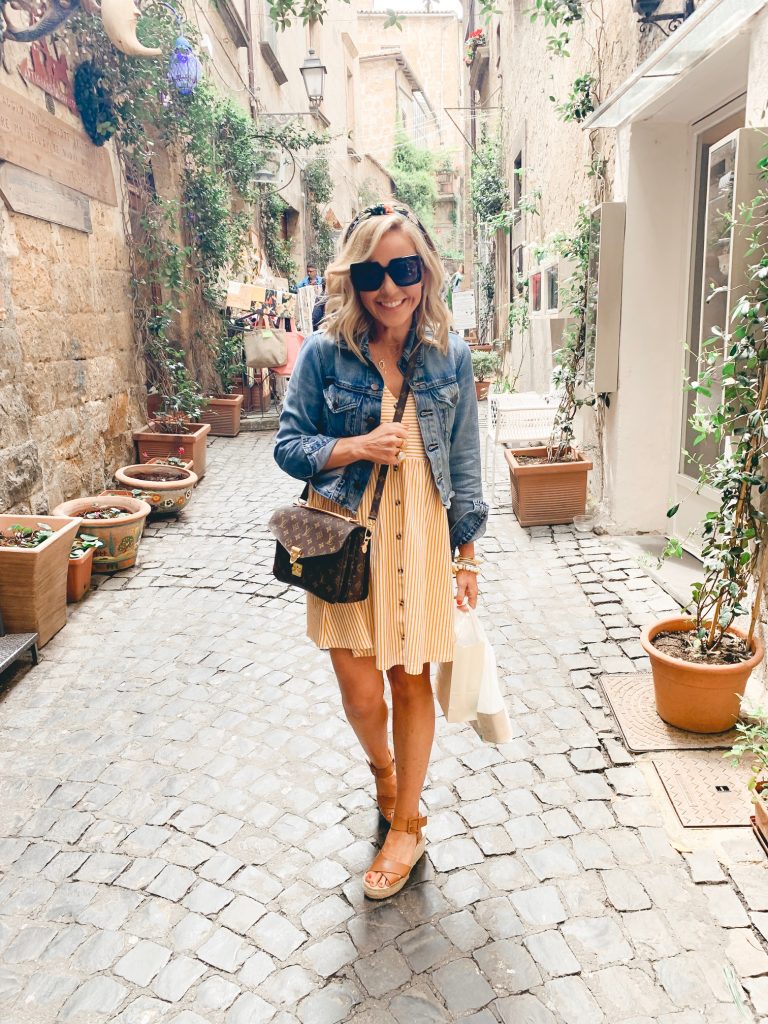 The Best Things to Do in Tuscany Italy featured by top US lifestyle blog Hello! Happiness; Image of a woman wearing denim jacket and striped dress.