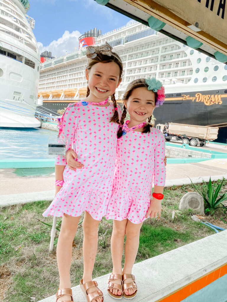 Disney Creators Celebration by popular Nashville lifestyle blog, Hello Happiness: image of two young girls standing in front of the Disney Dream cruise ship and wearing matching pineapple print dresses. 