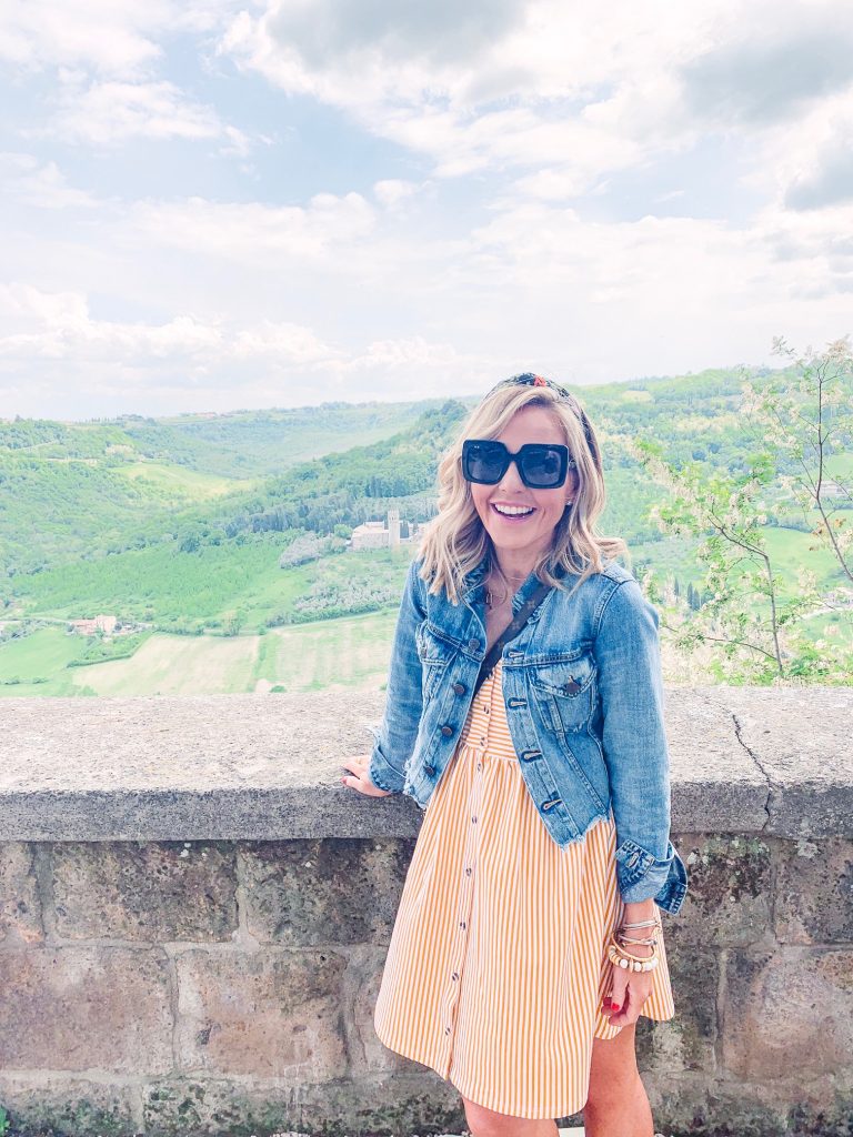 The Best Things to Do in Tuscany Italy featured by top US lifestyle blog Hello! Happiness; Image of a woman wearing denim jacket and striped dress.