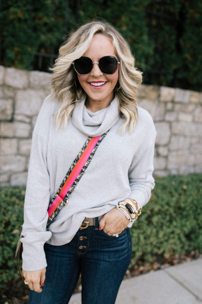 Gibsonlook by popular Nashville fashion blog, Hello Happiness: image of a Natasha Stoneking wearing a grey slouch neck sweater Gucci belt, sunglasses and button up jeans. 