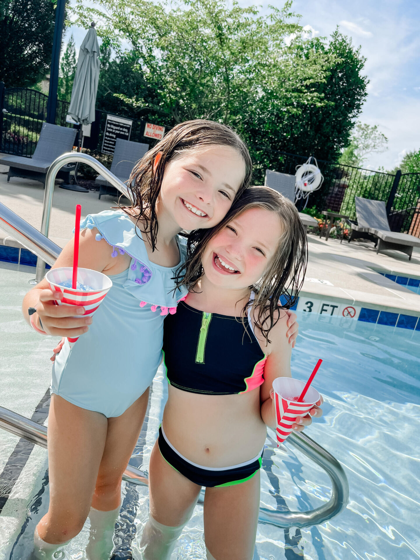 Walmart + Membership by popular Nashville lifestyle blog, Hello Happiness: image of two girls wearing swimsuits and eating snow cones in red and white stripe paper cups. 