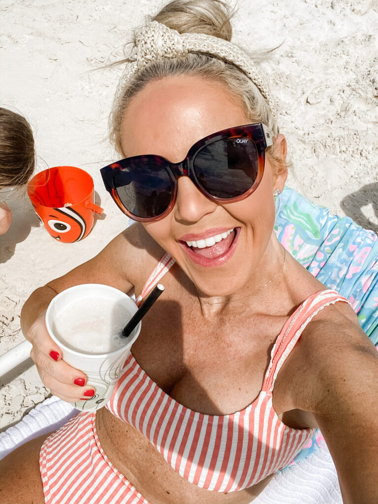 Disney Creators Celebration by popular Nashville lifestyle blog, Hello Happiness: image of a woman sitting in the sand at Castaway Cay Bahamas with a drink in her hand. 