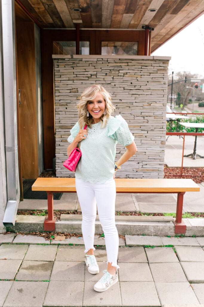 What COVID-19 Has Taught Me by popular Nashville lifestyle blog, Hello Happiness: image of a woman standing outside and wearing a mint eyelet top,destructed white jeans, yvett sneakers while holding a pink loulou bag.