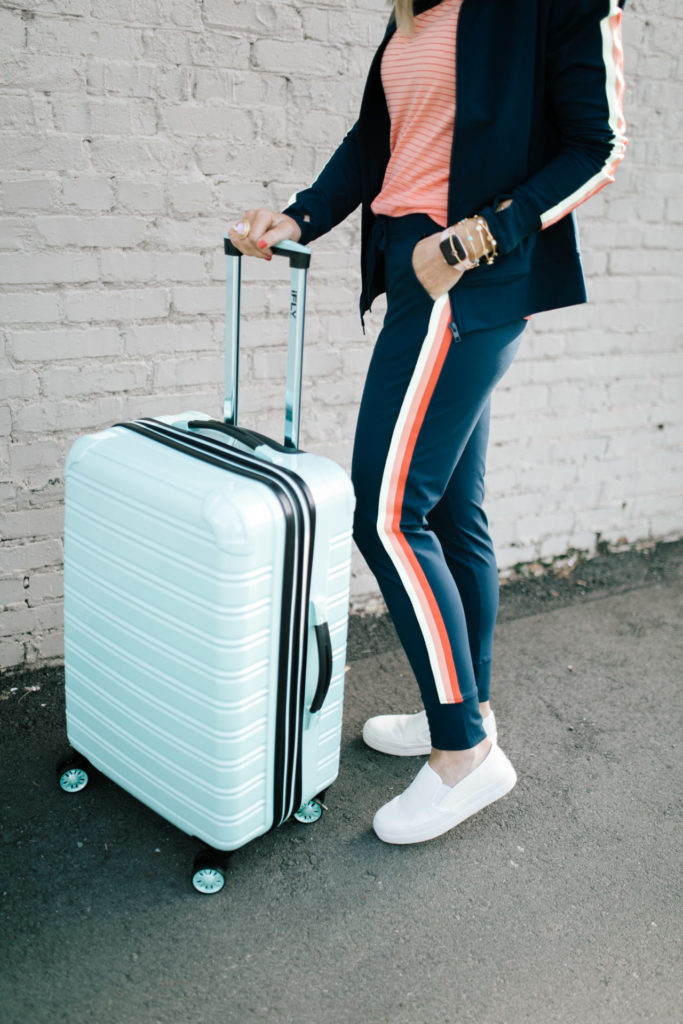 Cute Travel Outfit by popular Nashville fashion blog, Hello Happiness: image of a woman standing next to her Walmart iFly luggage wearing a Walmart Athletic Works Women's Performance Active Ombre Stripe Tank Top, Walmart Athletic Works Women's Athleisure Retro Stripe Track Jacket, Walmart Time and Tru Platform Twin Gore Slip On Sneaker, and Walmart Athletic Works Women's Athleisure Track Jogger Pants.