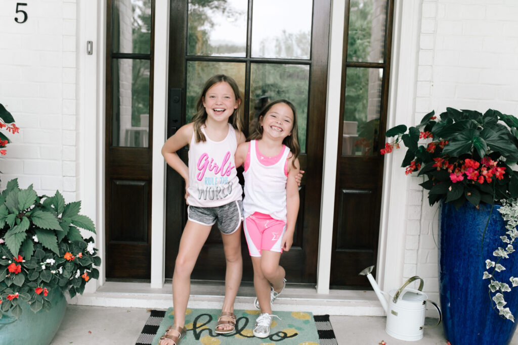 Walmart Back to School by popular Nashville life and style blog, Hello Happiness: image of two young girls standing outside and wearing a Walmart Cheetah Girls Graphic Racerback Performance Tank Top and Running Shorts and Walmart Athletic Works Girls Active 2-Fer Tank and Bike Printed Bike Shorts.
