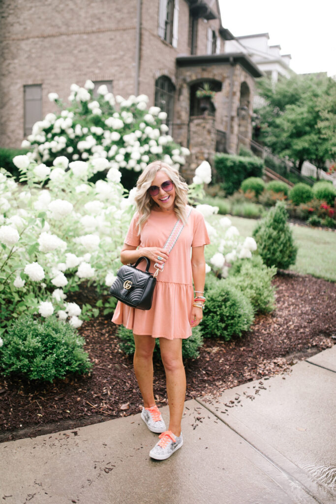 Football Game Outfits by popular Nashville fashion blog, Hello Happiness: image of Natasha Stoneking standing outside and wearing a ASOS Pull&Bear smock dress in washed coral and sneakers and carrying a Gucci Marmot purse with a Social Threads strap. 