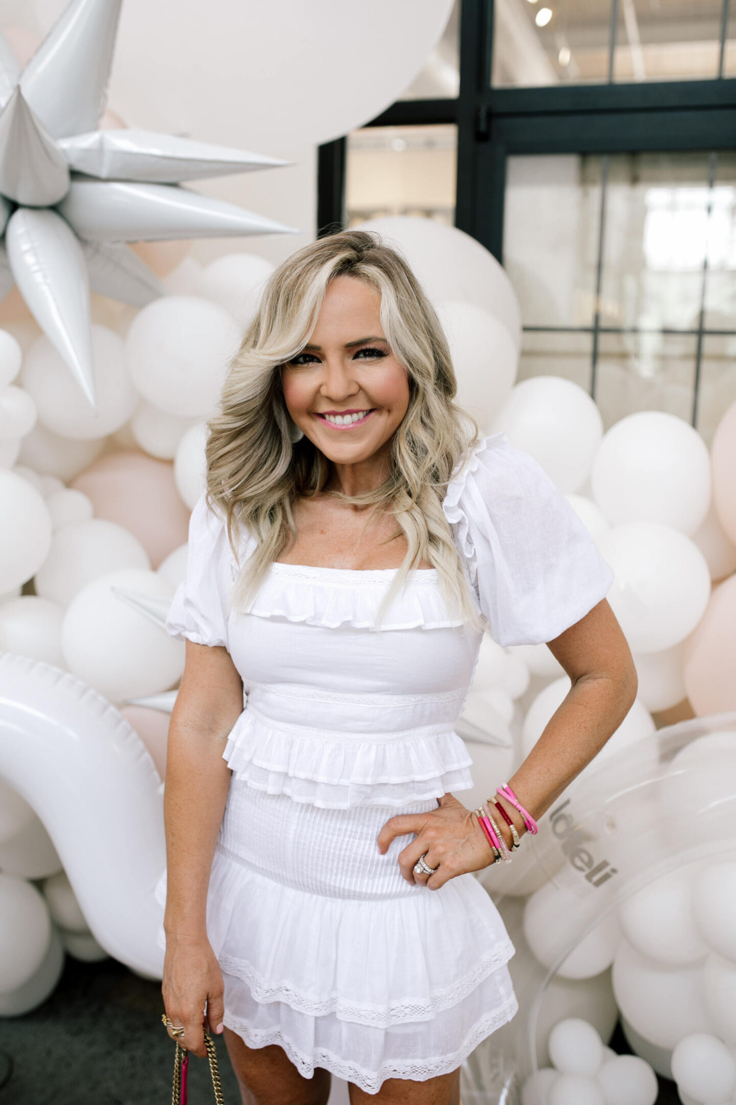 Revolve Clothing by popular Nashville fashion blog, Hello Happiness: image of Natasha Stoneking standing by a white balloon garland and wearing a white Revolve dress and holding a pink YSL bag. 