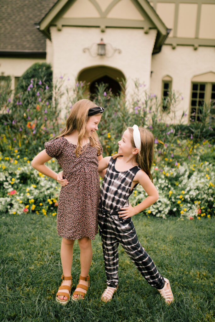 Tween Fashion by popular Nashville fashion blog, Hello Happiness: image of two girls standing together outside and wearing a Target tie dye jump suit, gladiator sandals, white knot headband, Target skater ditsy print swing dress, and brown espadrille sandals. 