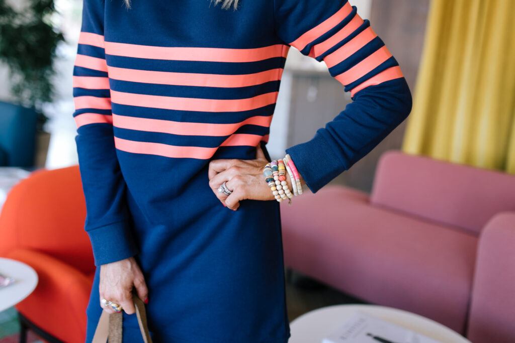 Sail to Sable by popular Nashville fashion blog, Hello Happiness: image of a woman wearing a Sail to Sable ORANGE STRIPE SWEATSHIRT DRESS, FULL IMAGE ZAGA SNEAKERS IN SAND SPOTTED, and holding a Bagging Rights TOTE-ALLY Bag.