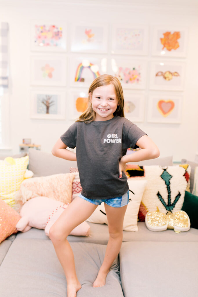 Tween Fashion by popular Nashville fashion blog, Hello Happiness: image of a girl standing on a grey couch and wearing Target gym shorts and a Target Girl Power t-shirt. 