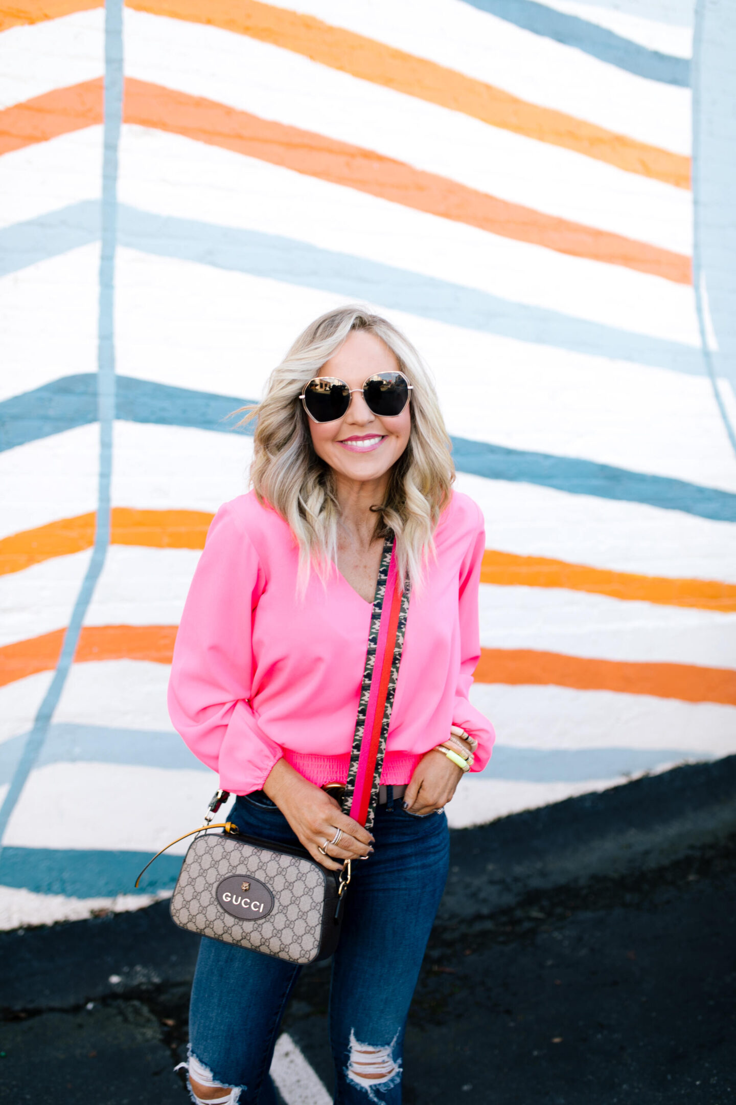 Sail to Sable by popular Nashville fashion blog, Hello Happiness: collage image of Natasha Stoneking wearing a Sail to Sable v-neck hibiscus top, Good American jeans and Gucci camera bag with a camo colorblock strap. 