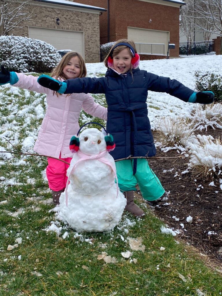 Year in Review by popular Nashville lifestyle blog, Hello Happiness: image of two young girls building a snowman outside. 