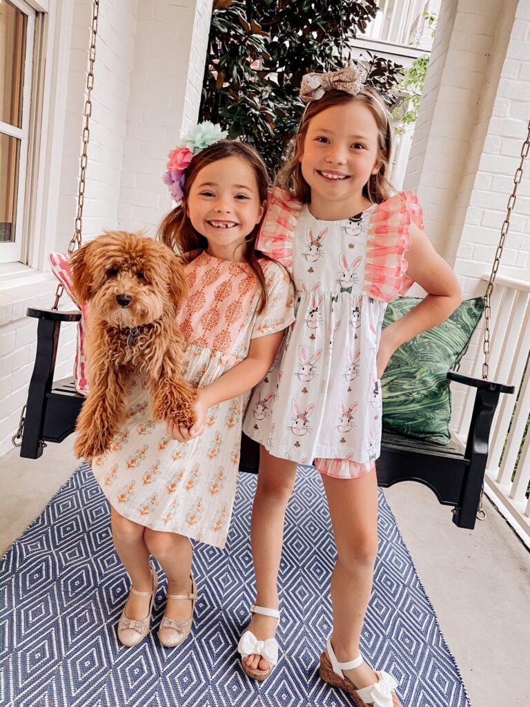 Year in Review by popular Nashville lifestyle blog, Hello Happiness: image of two young girls standing together on their front porch and holding their doodle breed dog. 
